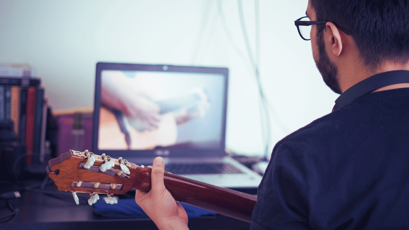 Studente di chitarra che segue una lezione online da casa, con un insegnante su uno schermo, in un ambiente accogliente con una chitarra e decorazioni musicali.