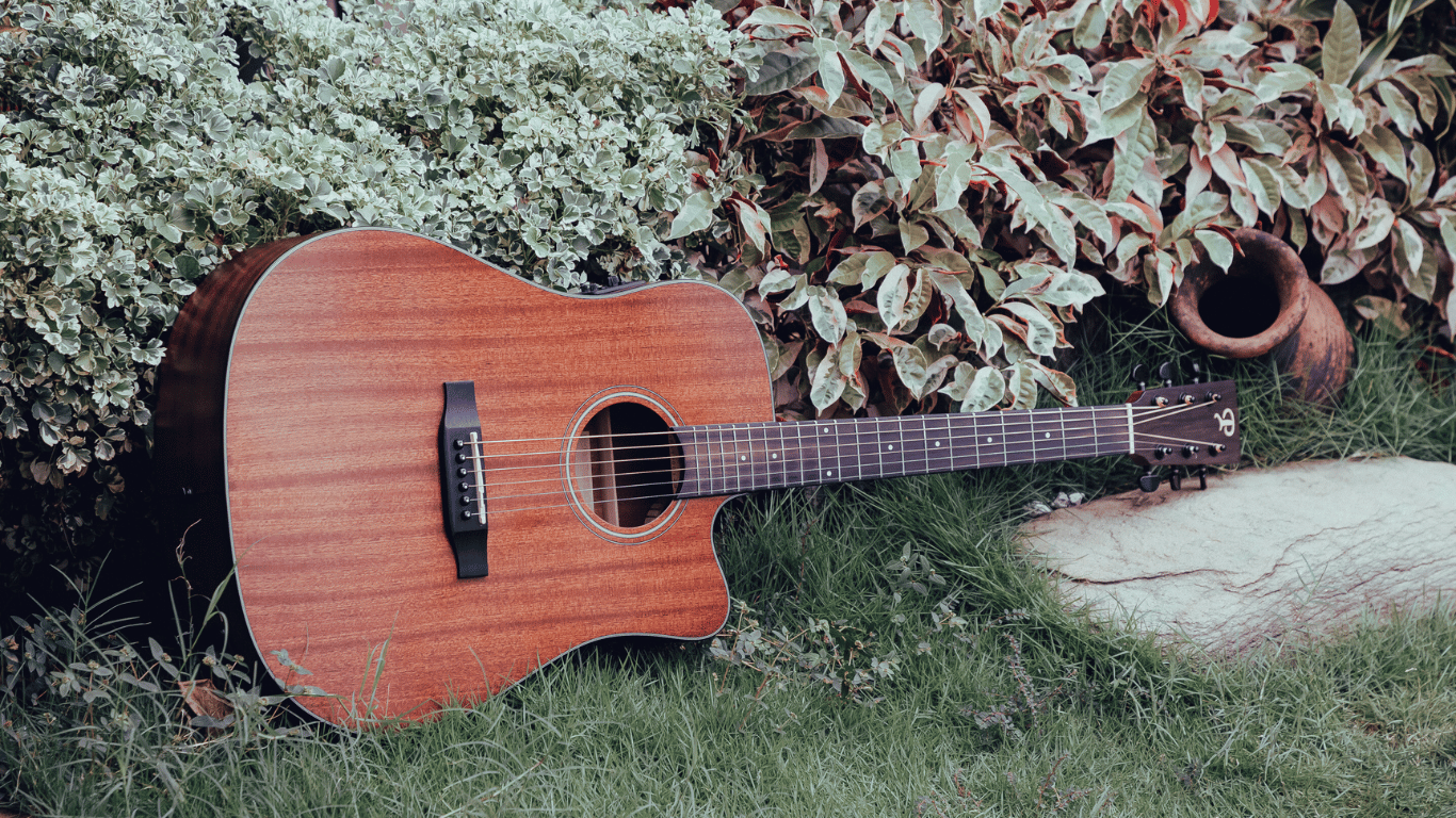 Musicista che suona la chitarra all'aperto, in un ambiente naturale, con un'espressione serena e rilassata, godendosi il momento.